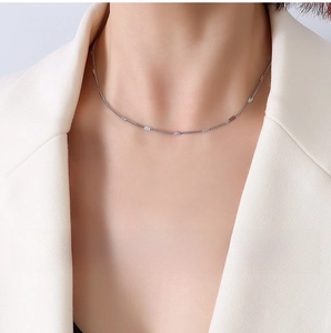Detailed view of 1.4mm flat curb chain in steel finish worn by a model in a white blazer