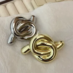 Detailed close-up of geometric knot metal hair clips in polished gold and silver finishes