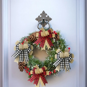 Christmas wreath with buffalo plaid bows, pine cones, and berries on a vintage door