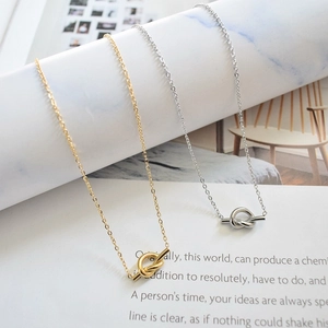 Close-up of gold and silver knot pendant necklaces on white marble and magazine props