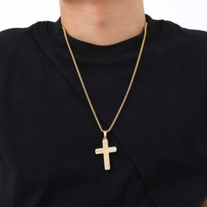 Close-up of gold stainless steel cracked cross pendant necklace worn on a black shirt