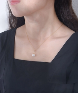 Detailed view of elegant white pearl pendant with tiny rhinestones on a gold chain necklace