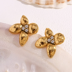 Detail view of 18K gold plated floral stud earrings with micro-set zircons on shell background