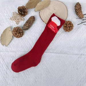 Detail of red Christmas knit socks with a festive mini boot ornament and embroidery