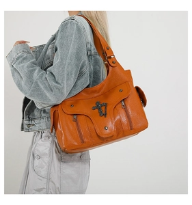 Detailaufnahme der orangefarbenen Schultertasche aus Leder mit Kreuz-Metalldekor