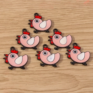 Macro shot of cartoon chicken enamel charms for DIY jewelry making on wooden background