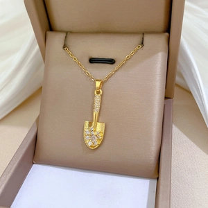 Close-up of golden shovel pendant with sparkling cubic zirconia on fine chain