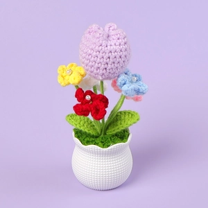 Macro detail of a handmade crochet purple tulip and colorful flowers in a ceramic pot