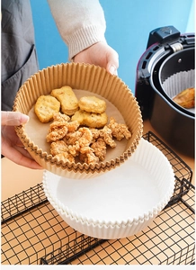 Brown and white air fryer liners with scalloped edges used for crispy fried chicken