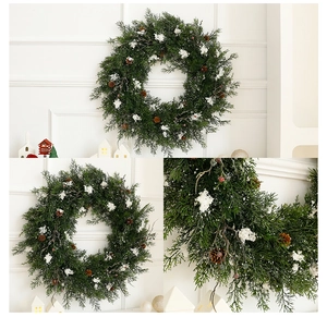 Close-up of artificial Christmas wreath with snowy cedar branches and pine cones