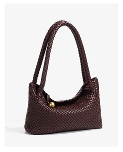 Detail of dark brown woven leather tote bag featuring a golden spherical metal ornament