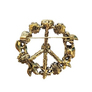 Vintage golden round rhinestone brooch with peace sign and baroque wreath design