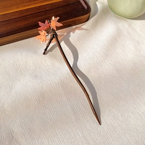 Detailed view of handmade wooden hair pin with translucent autumn maple leaf ornaments