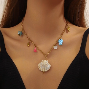 Gold-plated marine charm necklace featuring sea star, fish and shell pendants on a model