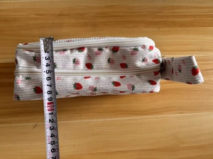Vertical height measurement of a white corduroy strawberry pencil case showing 9cm size
