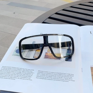 Oversized black sports goggles with transparent lens displayed on a fashion magazine