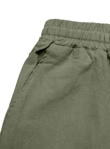 Detailed macro view of the elastic drawstring waistband and olive linen fabric texture