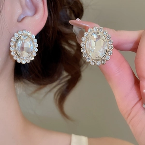 Close-up of sparkling oval crystal halo stud earrings with gold plating and fine stones