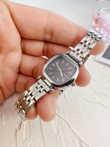 Detail of square silver metal watch with dark grey dial and minimalist baton markers