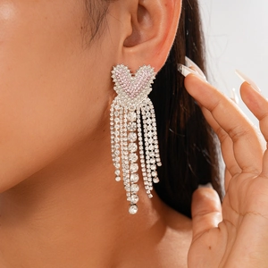 Macro detail of luxury heart earrings with sparkling pink diamonds and silver tassels
