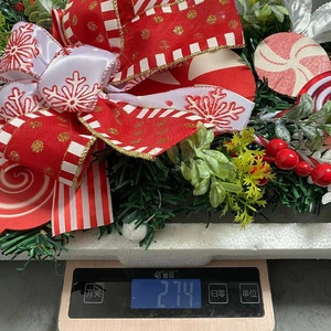 Detailed view of candy Christmas teardrop swag weighing 274g on a digital scale