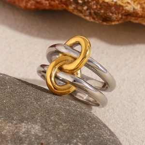 Detail of two-tone 18K gold plated knotted double-layer ring on a natural stone surface