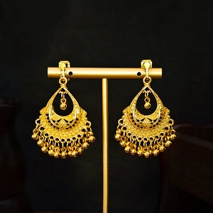 Detailed view of gold teardrop tassel earrings with bohemian ethnic style on a stand