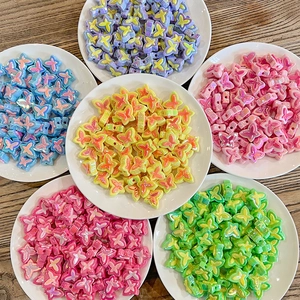 Colorful butterfly beads for DIY crafts displayed in white bowls on a wooden table