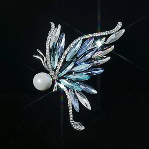 Broche papillon argentée avec cristaux bleus et perle sur fond noir élégant