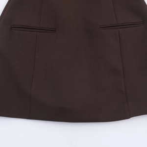 Detail view of coffee brown dress featuring symmetrical decorative pockets and smooth texture