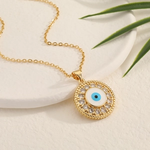 Close-up of gold Evil Eye necklace with zircon inlay on a white stone pedestal