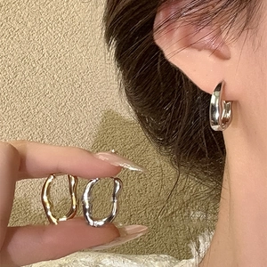 Detail of twisted geometric metal hoop earrings in gold and silver finishes on a model