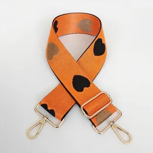 Detail of orange nylon bag strap with heart patterns and gold metal lobster clasps