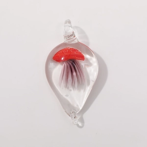 Macro detail of teardrop glass pendant featuring a red jellyfish design inside
