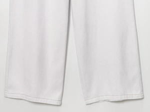 Détail du pantalon de jogging blanc montrant la double couture et la texture du sergé