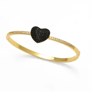 Dettaglio di bracciale placcato oro 18k con cuore e zirconi neri e bianchi incastonati
