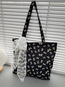 Detail of black canvas tote bag with bow prints and white lace ribbon decoration