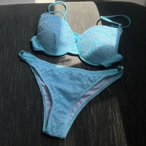 Light blue lace bikini set with underwire cups and hollow mesh texture on a dark fabric