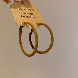 Detail view of large copper hoop earrings wrapped in brown velvet with a vintage aesthetic