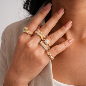 Detail of luxury 5-piece gold ring set with crystals and green gemstone on hand
