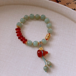 Detail of jade and agate bead bracelet with golden hollow spacers and a red gourd pendant