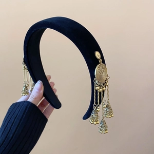 Detail of black velvet headband featuring golden bell tassel chains in ethnic style