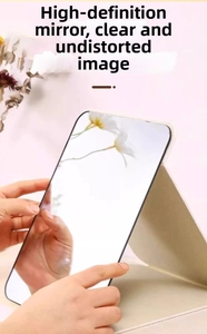 Close-up of portable folding makeup mirror with beige leather cover and clear reflection