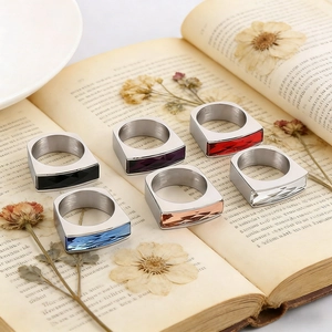 Detailed close-up of six stainless steel rings with rectangular crystals on vintage book pages