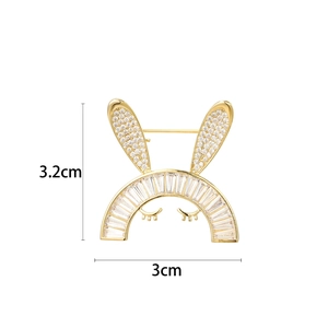 Broche lapin mignonne avec zircons et cils dorés sur un fond blanc neutre