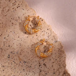 Detail of twisted 18K gold plated hoop earrings with shimmering pave-set zircon crystals