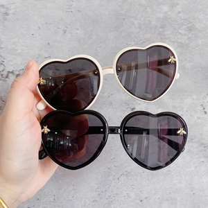Detail of heart-shaped kids sunglasses featuring decorative gold bee on the frames