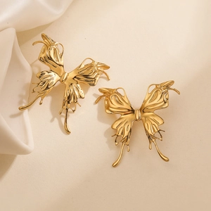 Textured gold butterfly stud earrings made of stainless steel on silk background