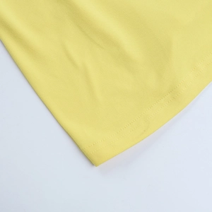 Détail du tissu en maille jaune vif avec des finitions de couture à double aiguille