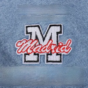 Detailed close-up of heavy embroidery with Madrid lettering on blue denim fabric